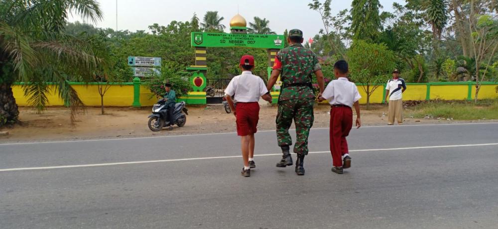 Anggota Koramil 03/Bgs Bantu Seberangkan Siswa SD 007 di Jalan